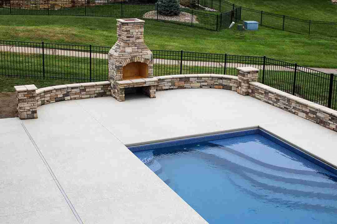 Outdoor fireplace with safe clearance beside a pool deck